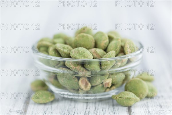 Peanuts (with Wasabi flavor) on an old wooden table as detailed close-up shot (selective focus)