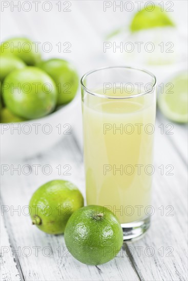 Fresh Lime Juice as high detailed close-up shot on a vintage wooden table (selective focus)