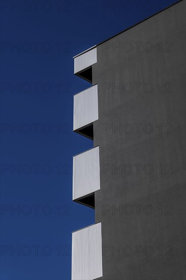 Beautiful Modern Concrete Design Building with Metal Balcony Against Blue Clear Sky in Switzerland