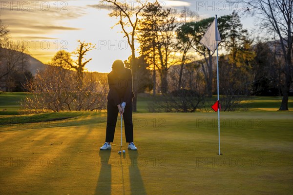 Female Golfer Concentration on the Putting Green on Golf Course in Sunset in Switzerland