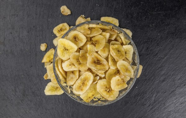Portion of Dried Banana Chips on a rustic slate slab, selective focus, close-up shot
