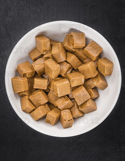 Portion of Caramel candy as detailed close up shot on a slate slab (selective focus)