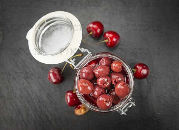 Portion of Preserved Cherries as detailed close up shot on a slate slab, selective focus