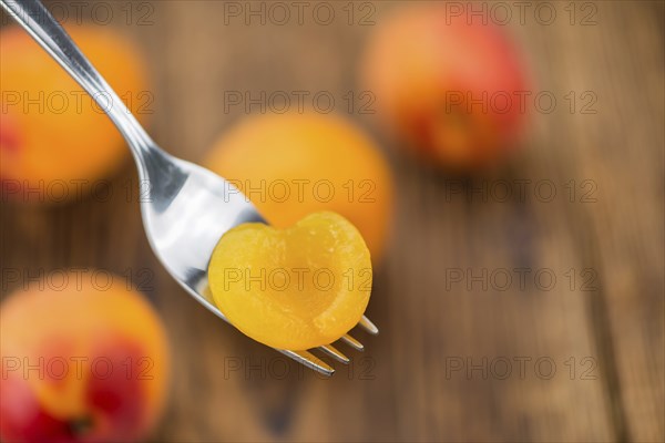 Canned Apricots on rustic wooden background (close-up shot)