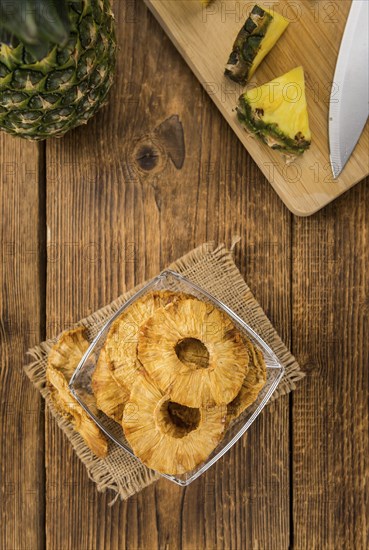 Pineapple rings (dried) on an old wooden table as detailed close-up shot, selective focus