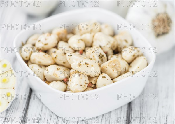 Marinated Garlic on an old wooden table as detailed close-up shot (selective focus)