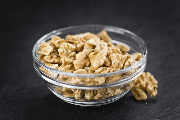 Portion of Cracked Walnuts on a rustic slate slab (selective focus, close-up shot)