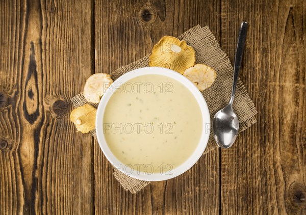 Chanterelle Soup as high detailed close-up shot on a vintage wooden table, selective focus