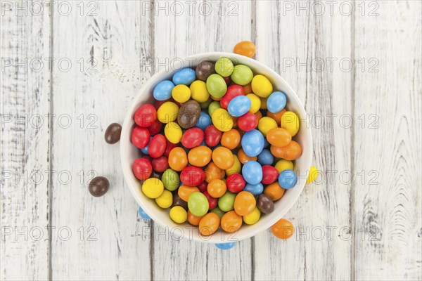 Cocolate coated Peanuts on rustic wooden background (close-up shot)