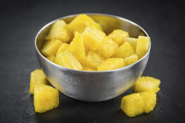 Portion of Sliced Pineapple as detailed close up shot on a slate slab, selective focus
