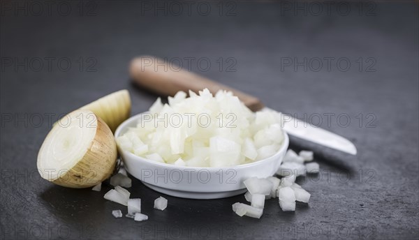 Portion of Chopped white onions as detailed close up shot on a slate slab, selective focus