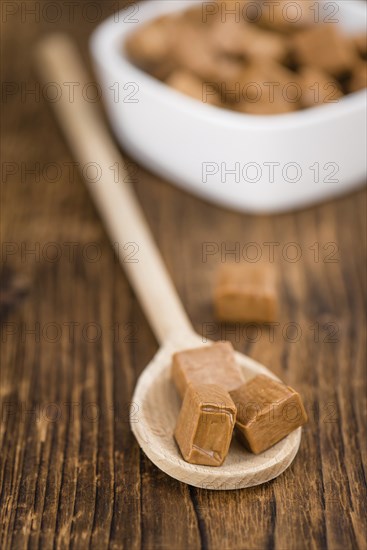 Portion of homemade Caramel on wooden background (selective focus, close-up shot)