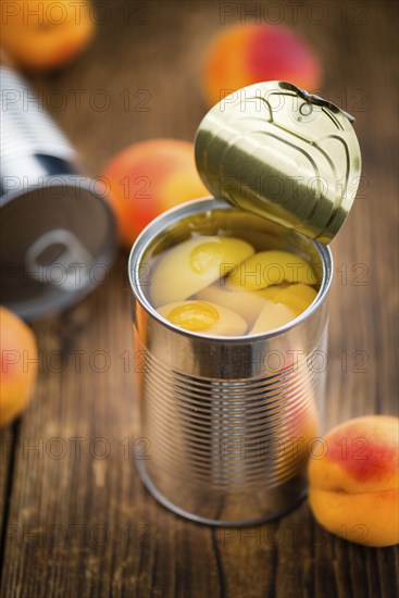 Canned Apricots on an old wooden table as detailed close-up shot (selective focus)
