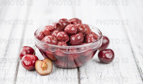 Canned Cherries as high detailed close-up shot on a vintage wooden table, selective focus