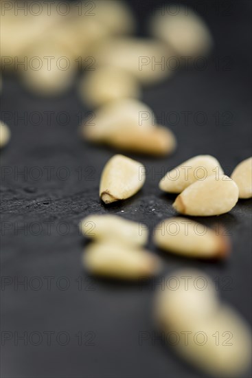 Portion of Pine Nuts as detailed close up shot on a slate slab (selective focus)