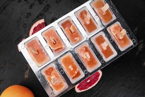 Some homemade Grapefruit Popsicles (with some fresh fruits) as close-up shot (selective focus)