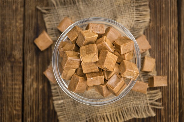 Caramel pieces as high detailed close-up shot on a vintage wooden table (selective focus)