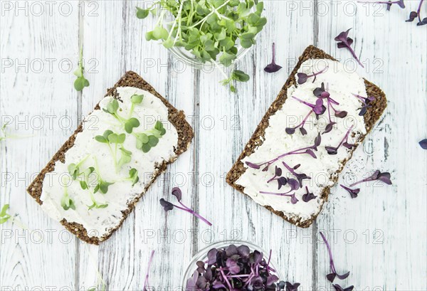 An old wooden table with healthy food (slice of bread, cream cheese and fresh cutted cress),