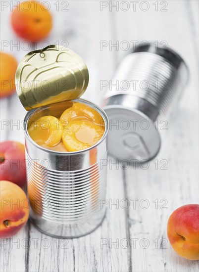 Canned Apricots on rustic wooden background (close-up shot)