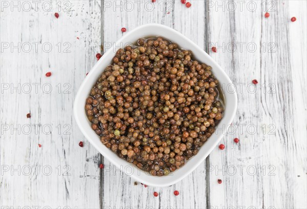 Fresh made Pink Peppercorns (preserved) on an old and rustic wooden table, selective focus,