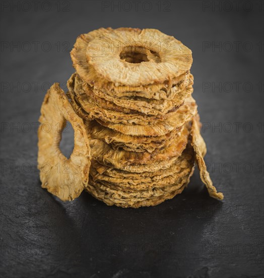 Portion of Dried Pineapple Rings on a rustic slate slab, selective focus, close-up shot