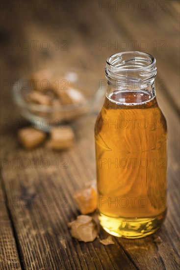 Caramel Syrup as high detailed close-up shot on a vintage wooden table (selective focus)