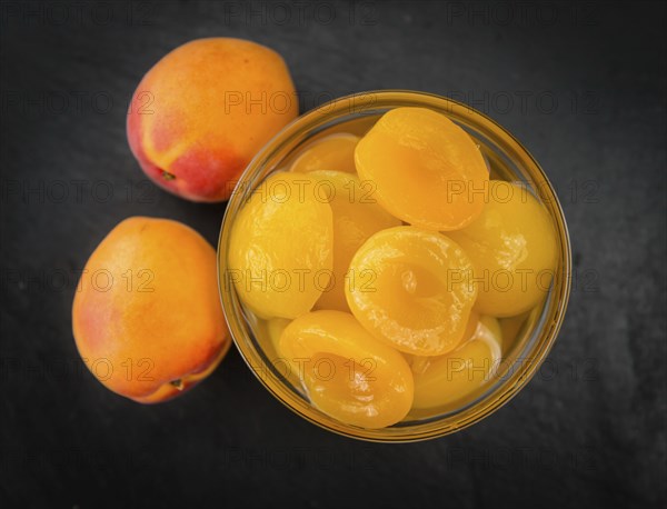 Portion of Canned Apricots as detailed close up shot on a slate slab (selective focus)