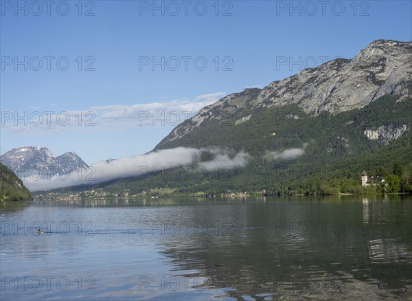 Morning mist drifts over a forest, Grundlsee in the morning light, near Gössl, Salzkammergut,
