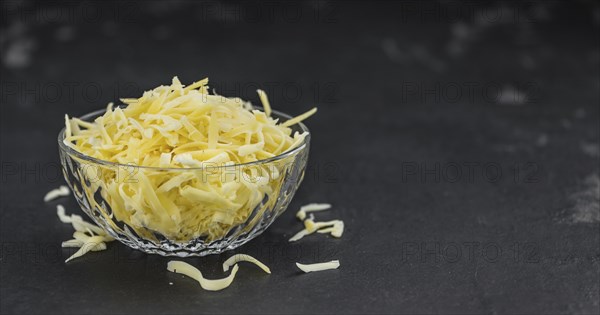 Homemade Grated Cheese (close-up shot) on a vintage slate slab
