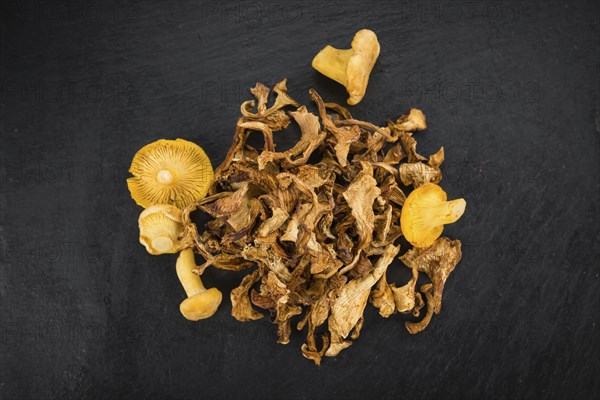 Portion of Dried Chanterelles as detailed close up shot on a slate slab, selective focus