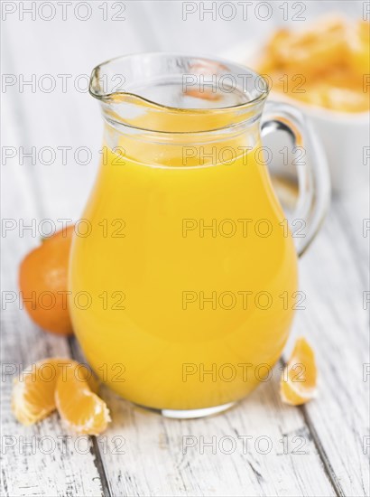 Homemade Tangerine Juice on an old and rustic wooden table (selective focus, close-up shot)