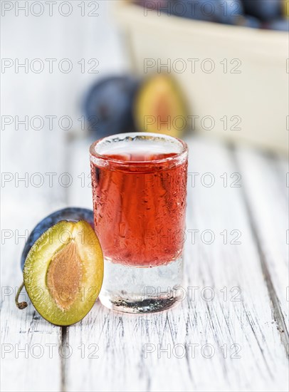 Plum Liqueur on rustic wooden background as close-up shot
