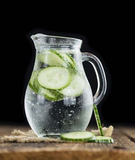 Fresh made Cucumber Water as high detailed close-up shot on a vintage wooden table, selective focus