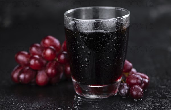 Portion of healthy Red Grape Juice on a slate slab (selective focus)