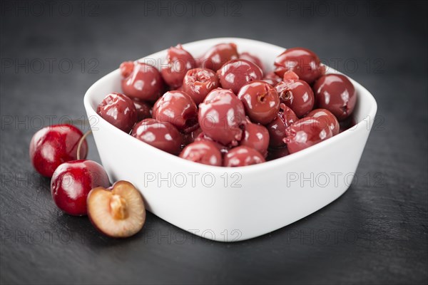 Portion of Preserved Cherries as detailed close up shot on a slate slab, selective focus