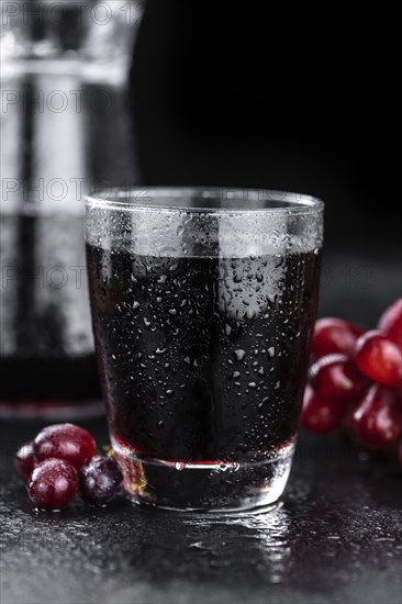 Portion of healthy Red Grape Juice on a slate slab (selective focus)