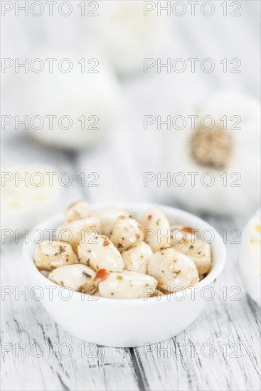 Garlic (preserved) as high detailed close-up shot on a vintage wooden table (selective focus)