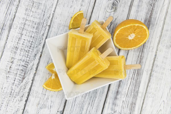 Orange Popsicles (selective focus, close-up shot) on a vintage background