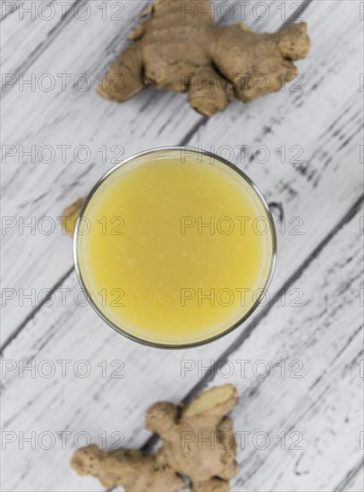 Healthy Ginger Sap on a wooden table as detailed close-up shot (selective focus)