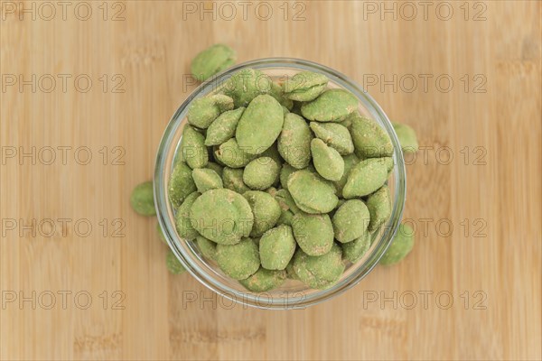 Peanuts (with Wasabi flavor) on an old wooden table as detailed close-up shot (selective focus)