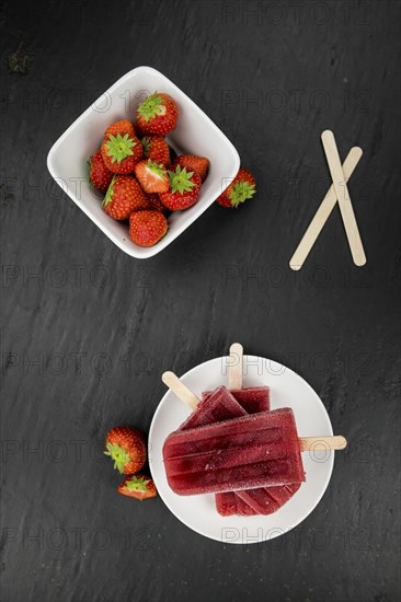Homemade Strawberry Popsicles (close-up shot, selective focus) on vintage background