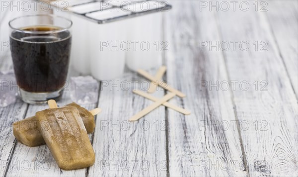 Fresh made Cola Popsicles on wooden background (selective focus, close-up shot)