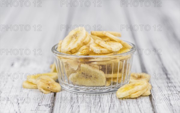 Homemade Dried Banana Chips on an wooden table as detailed close-up shot, selective focus