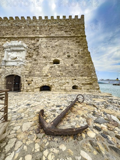 Old historical cane anchor made of iron slightly rusty in front of main gate entrance of fortress