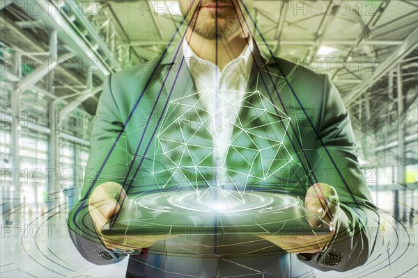 A man in a suit holds a holographic object in a green high-tech factory hall that looks futuristic,