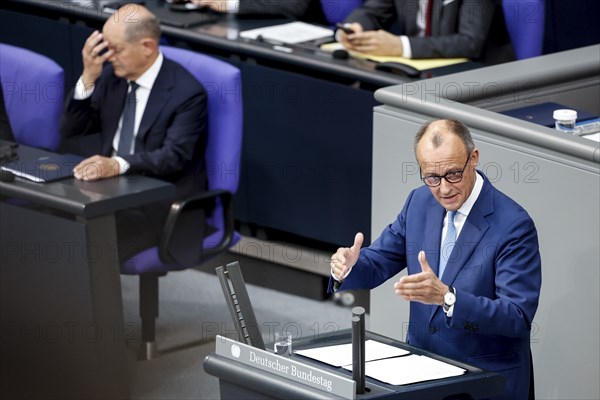 CDU parliamentary group leader Friedrich Merz, right, speaks in the Bundestag, in the background is