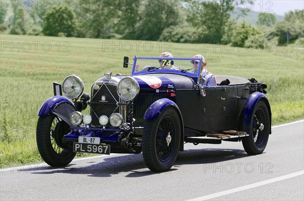 Black convertible with driver and passenger on a country road during a rally, classic car, car