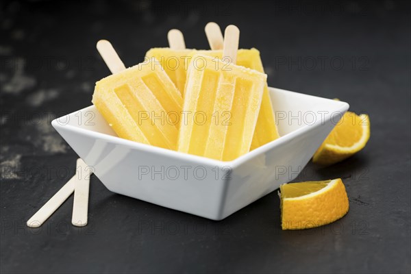 Orange Popsicles (selective focus, close-up shot) on a vintage background