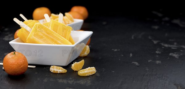 Homemade Tangerine Popsicles with some fresh fruits (close-up shot) on a vintage background