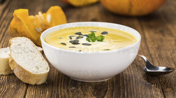 Portion of fresh made Pumpkin Soup (close-up shot) on rustic background